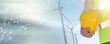 Engineer holding yellow helmet with wind turbines on background; panoramic banner