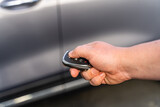 Fototapeta  - Man opening his car door with the control remote key. Car remote control by smart key.