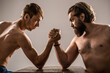 © Yevhen - Two man's hands clasped arm wrestling, strong and weak, unequal match. Arm wrestling. Arms wrestling thin hand, big strong arm in studio