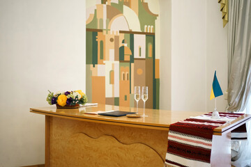 Wall Mural - Hall of wedding ceremonies with a table with glasses, a book and a Ukrainian flag.