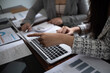 © Supitnan - Cropped image of professional businesswoman, entrepreneur or accountant working on a financial report paperwork at her desk, using calculator or laptop