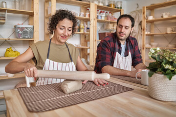 Wall Mural - Woman having fun while molding a piece of clay in a pottery workshop. Craft and hobby concept.