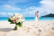 Close-up view of a wedding floral bouquet on sand beach with bride and groom kissing. Summer tropical vacation concept.