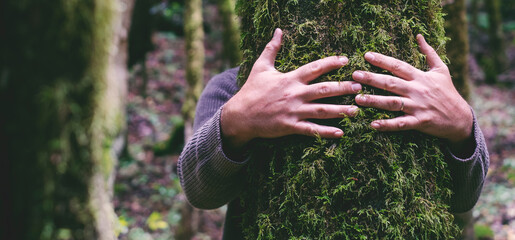 love for nature concept with man hands hugging bonding green musk trunk tree in the forest woods. en