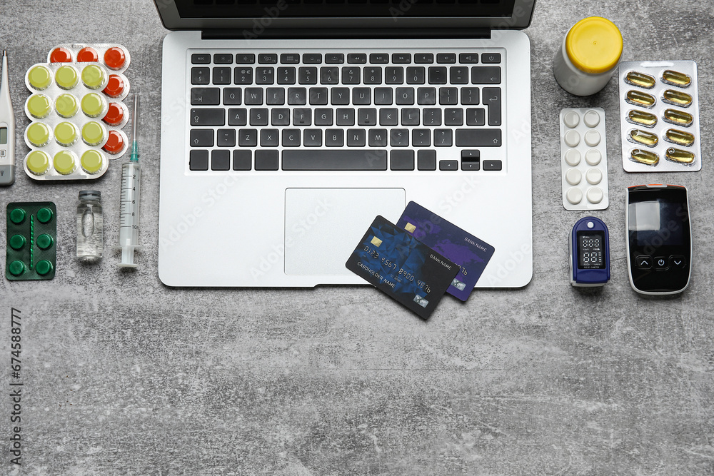 Laptop, credit cards and items from first aid kit on grunge grey background