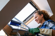 © Barillo Images - Brunette woman cleaning roof light window at home using squeegee. House work and domestic lifestyle.