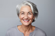 © Fortis Design - An Overflow of Joy: A Portrait of a Smiling, Happy, Mature Woman with Gray Hair against a Plain Gray Backdrop