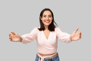 Poster - Young woman opening arms for hug on light background