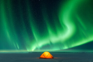 Wall Mural - Orange tent lighted from the inside against the backdrop of incredible sky with Northern lights. Aurora borealis in winter field