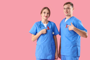 Sticker - Young male and female doctors with red ribbons on pink background. World AIDS day concept