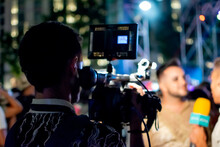 Camera Man Recording Television Reporter During Interview At Live Event At Night