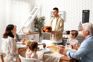 Sticker - Young man bringing turkey at festive table with his family on Thanksgiving Day