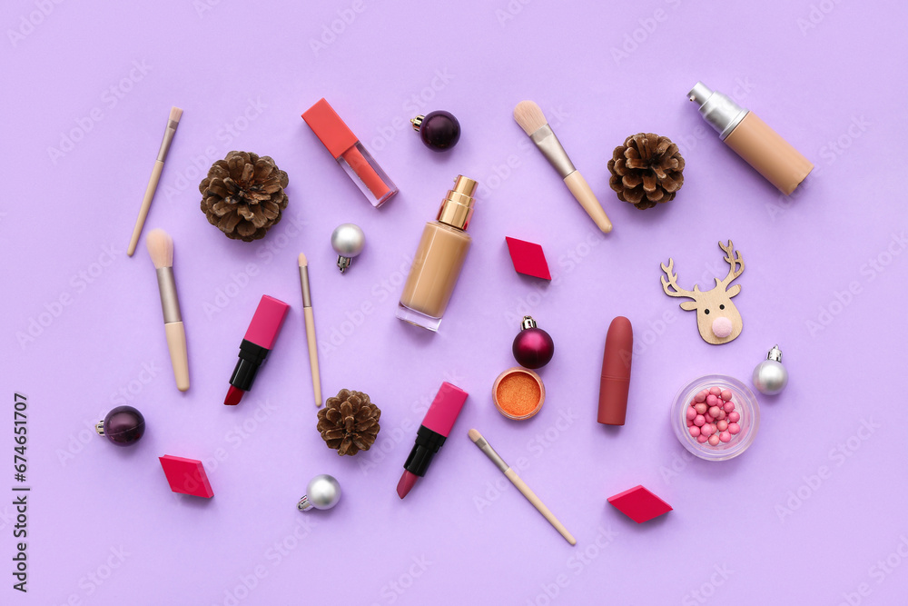 Different decorative cosmetics with Christmas balls and cones on lilac background