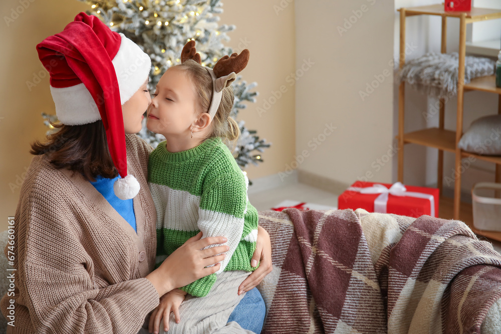 Young mother and her little daughter touching noses at home on Christmas eve