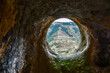 © ako-photography - A round window in a sandstone cave with a view of the opposite mountain. Selective focus