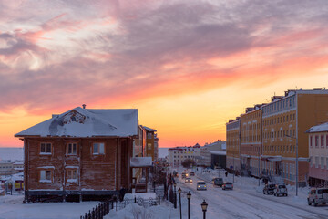 Wall Mural - Morning view of a snow-covered street in a northern town in the Arctic. Winter city landscape. Cars on the street. Cold weather. Beautiful sunrise. The city of Anadyr, Chukotka, Far North of Russia.