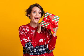 Poster - Portrait of impressed woman with stylish hairdo wear ornament sweater receive gift on christmas isolated on yellow color background