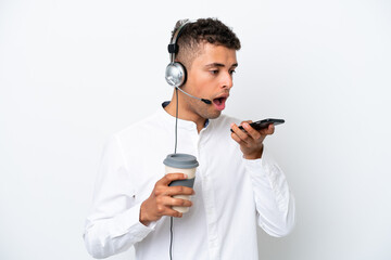 Wall Mural - Telemarketer Brazilian man working with a headset isolated on white background holding coffee to take away and a mobile