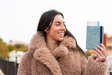 Wall Mural - Young woman holding a passport at outdoors with happy expression