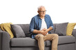 © Ljupco Smokovski - Mature man with abdominal pain sitting on a sofa isolated on white background