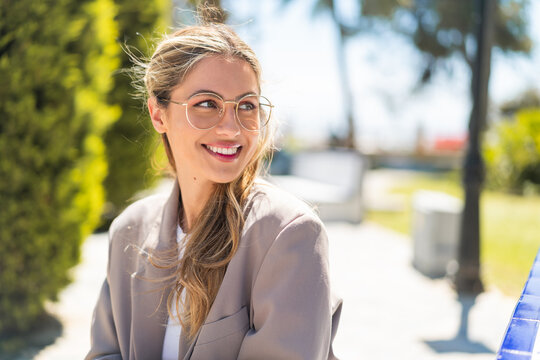 pretty blonde uruguayan woman with glasses at outdoors with happy expression