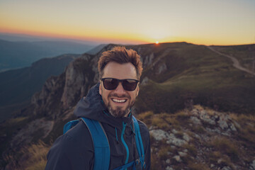 Fototapete - A smiling male traveler solo hiking the mountain adventure travel.