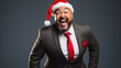 © MP Studio - A joyful man wearing a Santa hat, and a formal suit standing against a grey background, exuding a warm Christmas spirit.