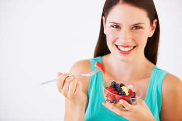 Poster - Food, fruit salad and portrait of woman with smile eating for nutrition, wellness and berry snack in studio. Health, happy and face of person for vitamins, diet and lose weight on white background