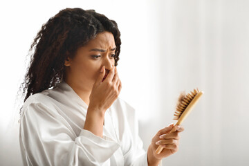 Wall Mural - Black Female Holding Brush Full Of Fallen Hair And Looking On It