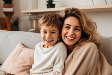 Wall Mural - Happy young mother and little son having fun on cozy couch in living room