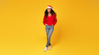 Joyful young black lady in Santa hat posing on yellow background, full length