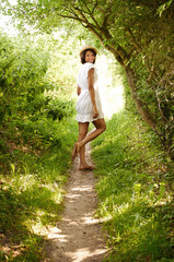 Poster - Portrait, smile and woman in hat in park in the countryside in summer, vacation and travel on holiday. Happy person in dress, woods and outdoor in nature at forest path, garden and field in Brazil