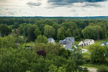 Low-density two story private homes in rural residential suburbs outside of Rochester, New York. Upscale suburban houses with large lot size and green grassy lawns in summer season