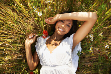 Poster - Portrait, above and woman in grass with flower in the countryside in summer, vacation and relax. Face, happy person in field on top view and poppy plant at farm in nature, garden or outdoor in Brazil