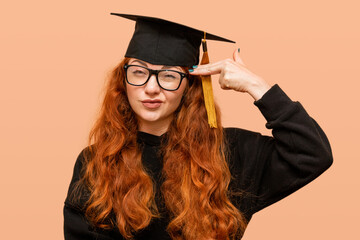 Wall Mural - Surprised graduate student points her finger at her head.  Young smart woman with red hair wearing glasses.