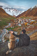 © oatawa - Tourist man with dog while sitting on Ushguli village in Georgia autumn.
