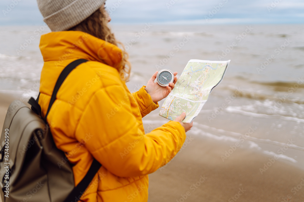 A young woman traveler with a compass and a map in her hands, reading a ...