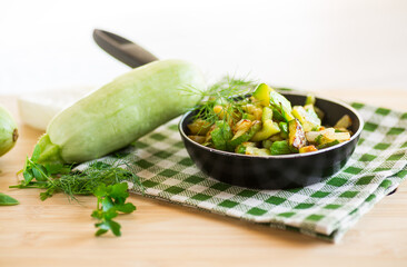 Wall Mural - Sliced zucchini fried with onions and herbs in a frying pan