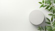 Empty round podium and green leaves on light grey background top view. Pedestal and fresh natural branches for cosmetic marketing. Eco product presentation or sale mockup. Top view. Minimal flat lay.