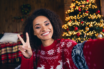 Sticker - Photo of adorable jolly girl dressed printed pullover new year ornament recording video streaming showing v-sign cozy decorations indoors