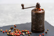 An old metal pepper and spice mill on slate tile, on light background.