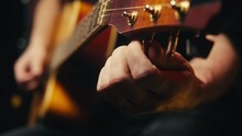 Young Musican Man Checking Strings Of Acoustic Guitar Close-up. Male Guitarist Tuning Sound Of Musical Instrument. 