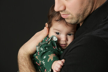 Studio portrait of father holding his little baby girl in green Christmas outfit, winter holiday, family memories, the first Christmas together