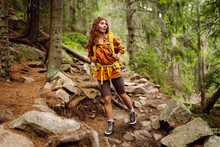 Smiling woman traveler along a forest hiking trail in the mountains against the backdrop of nature. Young woman with backpack traveling outdoors. Hiking, active lifestyle.