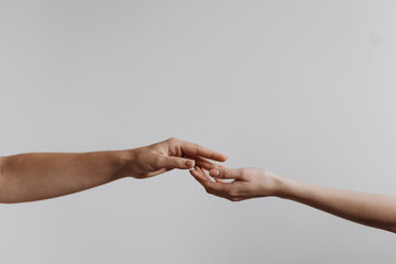 Hands touching each other isolated on grey background. Concept of human relation, community, togetherness, teamwork, love, symbolism, culture and history. 