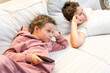 Children watching different channels on TV and boring. Children lying on comfotable sofa. Rest after school. 