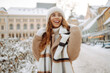 © maxbelchenko - Happy woman having fun on a snowy street on a frosty morning in winter. A young woman walks through the city on a winter day. Concept of walks, weekends.