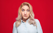 Confused young woman, isolated on red background. A girl with funny mouth grimace