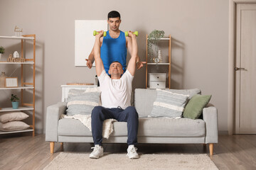 Sticker - Mature man training with dumbbells and rehabilitation therapist at home