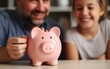 © piai - Daughter with father putting coin in piggy a bank at home